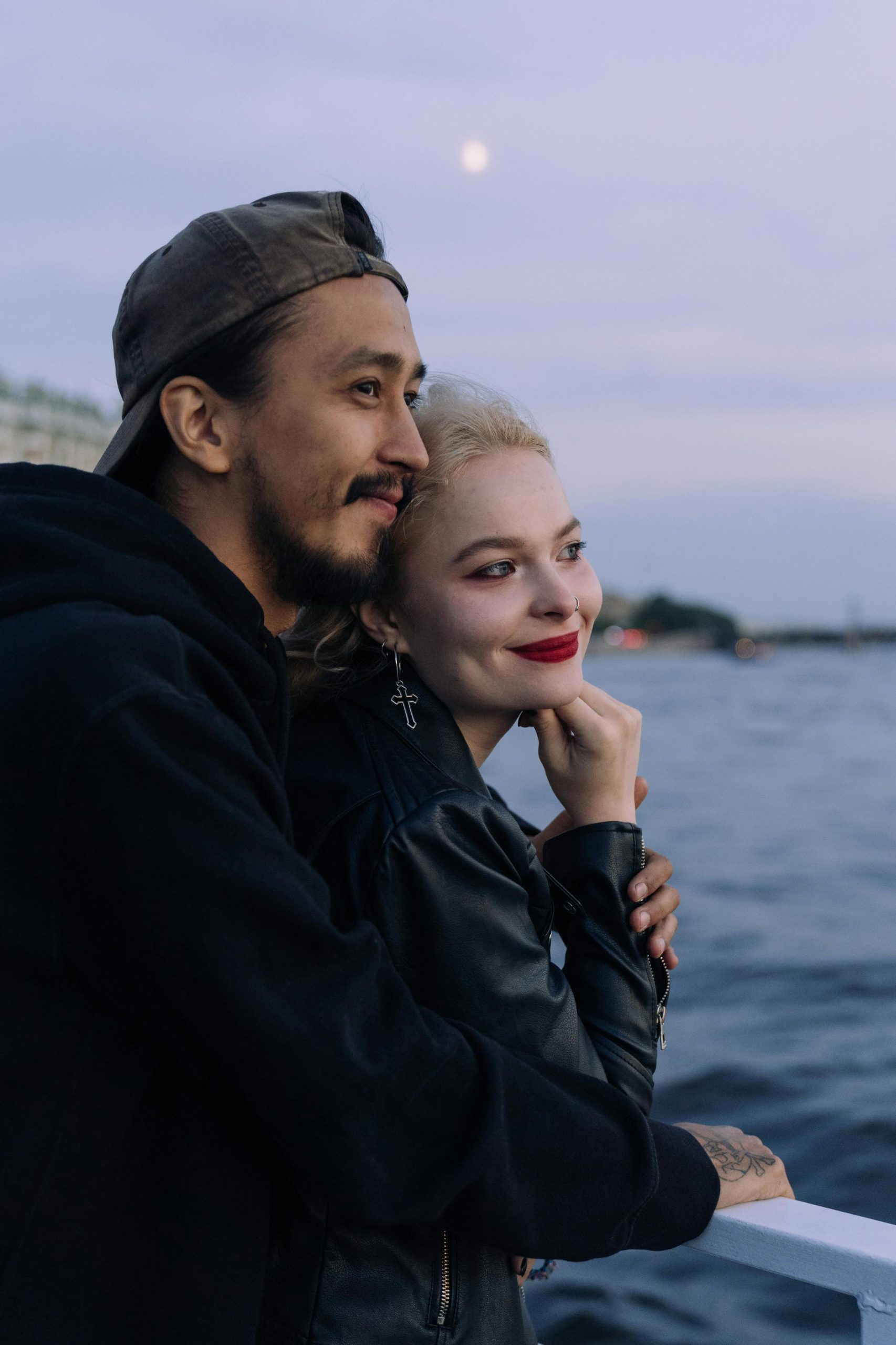 A romantic couple embraces while enjoying a scenic evening boat ride on the water.
